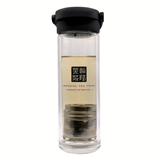Clear glass tea infuser with black lid on a white background